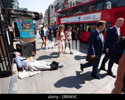 Geeignete Pendler, die an einem schlafenden Obdachlosen an der Liverpool Street Station London vorbeilaufen Stockfoto