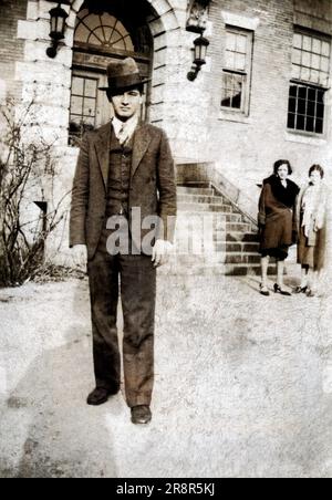 Ein eleganter Mann in einem dreiteiligen Anzug und einem Hut, vor einem Gebäude in Boston, Massachusetts, USA, 2 Frauen, die nebenan sind. Stockfoto