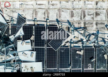Draufsicht der durch den Hurrikan Ian zerstörten Photovoltaik-Solarpaneele, die auf dem Dach des Industriebaues zur Erzeugung von ökologischem Strom montiert sind Stockfoto