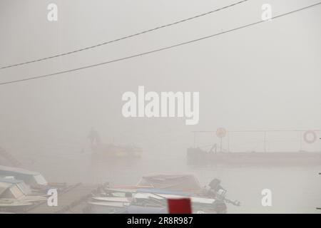 Garagen für Boote im Nebel unter einer Brücke am dnieper River am Morgen im Herbst Stockfoto