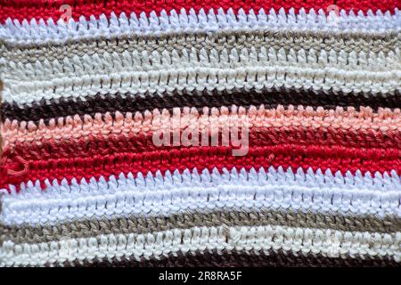 Gestreifter Teppich von Großmutter, mehrfarbig rot weiß schwarz als Hintergrund, Fußbodenteppich Stockfoto