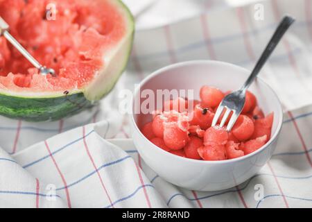 Wassermelonenbällchen in einer Schüssel mit einer Dessertgabel, neben einer ausgehöhlten Wassermelone Stockfoto