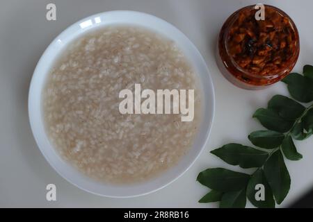 Kanji und Kadumanga. Reismehl mit Kerala Matta Reis. Aufgenommen mit Kerala-Mango-Gurke auf weißem Hintergrund. Stockfoto