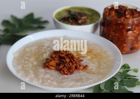 Kanji und Kadumanga. Reismehl mit Kerala Matta Reis. Serviert mit rohem Bananencurry und Kerala-Mango-Gurke. Auf einem weißen Hintern geschossen Stockfoto