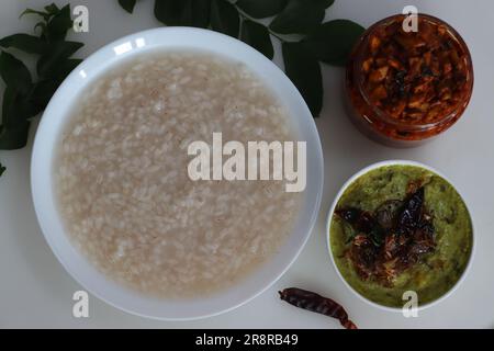 Kanji und Kadumanga. Reismehl mit Kerala Matta Reis. Serviert mit rohem Bananencurry und Kerala-Mango-Gurke. Auf einem weißen Hintern geschossen Stockfoto