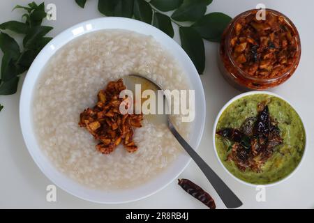 Kanji und Kadumanga. Reismehl mit Kerala Matta Reis. Serviert mit rohem Bananencurry und Kerala-Mango-Gurke. Auf einem weißen Hintern geschossen Stockfoto