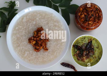 Kanji und Kadumanga. Reismehl mit Kerala Matta Reis. Serviert mit rohem Bananencurry und Kerala-Mango-Gurke. Auf einem weißen Hintern geschossen Stockfoto