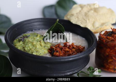 Kanji und Kadumanga. Reismehl mit Kerala Matta Reis. Serviert in Erdtopf mit Jackpot-Baumblatt-Besteck. Mit geschnittener Mango-Gurke, roh Stockfoto
