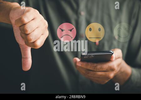 Unzufriedener Kunde, der ein Mobiltelefon in der Hand hält und ein Daumen-nach-unten-Zeichen mit einem grafischen ein-Sterne-Symbol anzeigt Stockfoto