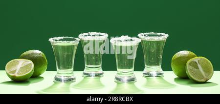 Aufnahmen von leckerem Tequila und Limetten auf grünem Hintergrund Stockfoto