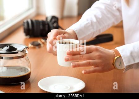 Eine Frau, die eine Tasse köstlichen Kaffees auf dem Fensterbrett hält Stockfoto