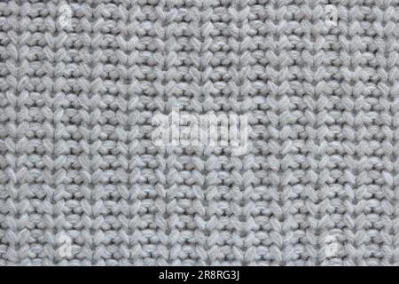 Strickmaterial aus einem dicken, grauen Faden mit gleichmäßigem Muster. Stockfoto