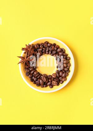 Rahmen aus Kaffeebohnen und Sternanis auf gelbem Hintergrund Stockfoto