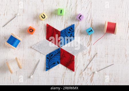 Das Wort QUILT besteht aus imitierten Schmuckwürfeln, die Nähzubehör umgeben Stockfoto