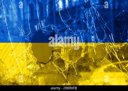 Einschussloch, Risse im Glas auf gelb-blauem Hintergrund. Ukrainische Flagge auf gebrochenem Glas. Konzept: Russisch-ukrainischer Krieg. Stockfoto