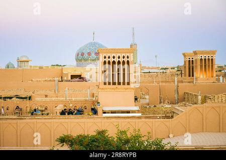 Yazd, Iran - 19. juni 2022: Blick auf Touristen im Café. Windfänger, Kuppeln, Minarette von Yazd bei Sonnenuntergang, Iran Stockfoto