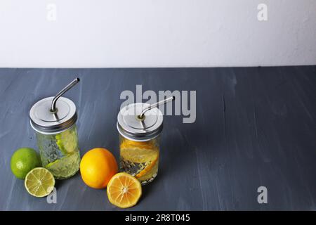 Limonade aus Zitrusfrüchten, Orange und Limette in Gläsern mit einer Pfeife auf grauem Hintergrund mit Platz für Text und Sommererfrischungen. Gesundes Wasser Stockfoto