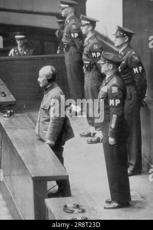 Urteil verabschiedet - Hideki Tojo, ehemaliger Ministerpräsident Japans und Kriegsführer, steht allein auf der Anklagebank, während sein Urteil vom 12. November vom Internationalen Militärgericht im Fernen Osten in Tokio verlesen wird. Hinten ist LT. Oberst S. Kenworthy, der für die Gefangenen verantwortlich ist. 29. November 1948. (Foto nach zugehörigem Pressefoto). Stockfoto