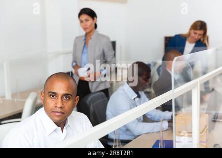 Erfolgreicher lateinamerikanischer Geschäftsmann, der am Arbeitsplatz die Kamera anschaut Stockfoto