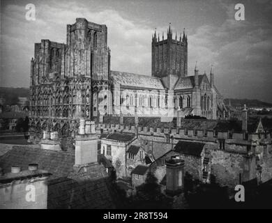 Wells Cathedral, Somerset -- Wells Cathedral, in der wunderschönen englischen Grafschaft Somerset, ist eine der schönsten Kirchen der Welt. Die herrliche Westfront, die hier von den Dächern der Stadt aus zu sehen ist, hat die Sonnenuntergänge seit mehr als siebenhundert Jahren gesehen. Es ist ein Wunder der aufwendigen Schnitzereien, mit über 600 Figuren Heiliger, Könige, Königinnen und Adligen, die in Nischen ruhen. 1. Januar 1953. (Foto der British Travel & Holidays Association). Stockfoto