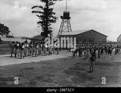 Tonga feiert hundertjähriges Jubiläum der Foundation of Kingdom Tonga Government Band leitet die Royal Navy Guard of Honour von H.M.S. Euryalus, der auch vier Naval Saluting Guns brachte, um sie der Königin von Tonga zu präsentieren, ihrer Majestät Königin Salote Tubou. 13. Dezember 1945. (Foto: Offizielles Foto der Royal Naval). Stockfoto