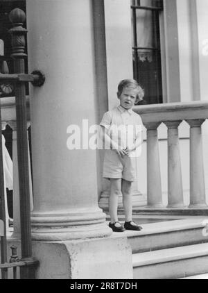 Prinz Edward sieht zu, wie Eltern nach Italien gehen – Prinz Edward schaut sich um eine Säule, während er seine Eltern gehen sieht. Der Herzog und die Herzogin von Kent verließen ihr Zuhause am Belgrave Square, London, für Hendon Aerodrme, wo sie in das Flugzeug des Königs einstiegen, um nach Florenz zu fliegen, zur Hochzeit des Herzogs von Spoleto, Sohn von König Victor Emmanuel von Italien, an Prinzessin Irene von Griechenland, Cousine der Herzogin. 30. Juni 1939. Stockfoto