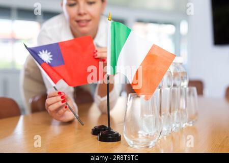 Vorbereitung auf Geschäftsverhandlungen - Frau setzt kleine Flaggen von Ländern Taiwans und Italiens auf den Tisch Stockfoto