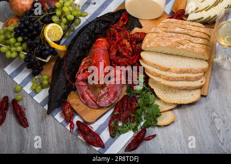 Geräucherter Stör, Hummer, Krebse, Brot, Käse und Früchte auf Holzoberfläche Stockfoto