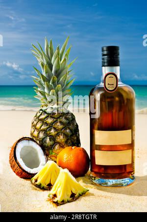 Rum-Flasche. Blick auf den tropischen Strand. Obst. Kokosnuss-Ananas-Modell. Stockfoto