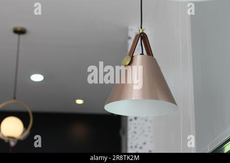 Eine cremefarbene konische Lampe hängt an der Decke, um Licht zu erzeugen. Stockfoto