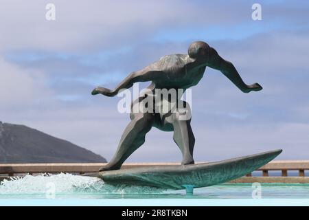 Bronzestatuen des spanischen Bildhauers José Castiñeiras Iglesias im Brunnen Los Surfistas, eine Hommage an Surfer, die die Wellen am Strand von Orzán zähmten. Stockfoto