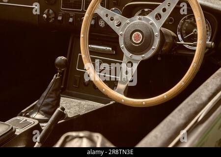 Das Innere eines 1970er MGB Roadsters mit MG-Logo, Armaturenbrett und Holzlenkrad. Britischer Sportwagen auf einer Oldtimer-Ausstellung. Stockfoto