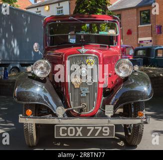 Vorderansicht eines roten Austin Seven aus den 1930er Jahren mit einem Startgriff, der aus dem Kühlergrill herausragt. Austin Ruby auf einer Oldtimer- und Oldtimershow. Stockfoto