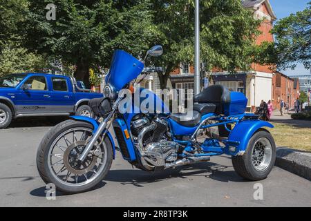 Ein blaues Dreirad parkt auf der Straße. Stockfoto