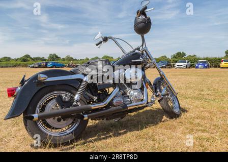 Die geparkte Harley Davidson mit einer schwarzen Lederjacke auf dem Sitz, die die Essenz der Rebellion einfängt, ruft den Nervenkitzel der offenen Straße hervor. Stockfoto