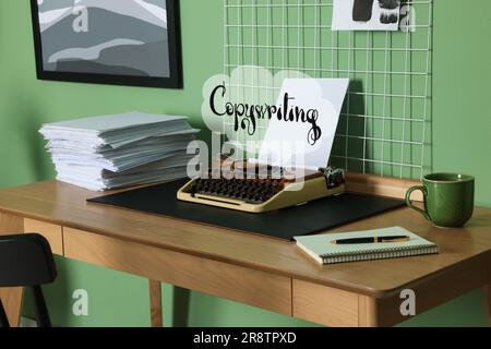 Thought Cloud mit Word Copywriting, Schreibmaschine, Papierstapel, Schreibwaren und Kaffee. Eleganter Arbeitsplatz mit Mood Board Stockfoto