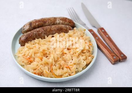 Teller mit Sauerkraut und Würstchen auf einem hellen Tisch Stockfoto