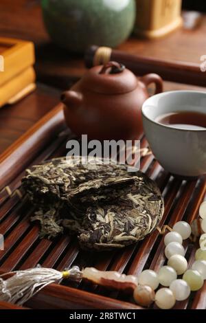 Aromatischer pu-erh-Tee und Gebetsperlen auf Holztablett, Nahaufnahme. Traditionelle Zeremonie Stockfoto