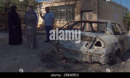 TURMUS AYYA, ISRAEL - JUNI 21: Die Palästinenser stehen neben einem Auto und einem Haus, die von israelischen Siedlern während eines Angriffs auf die Stadt Turmus Ayya in der Nähe der israelischen Siedlung Shilo am 21. Juni 2023 im Westjordanland, Israel, in Brand gesetzt wurden. Hunderte israelischer Siedler starteten einen Angriff auf die palästinensische Stadt Turmus Ayya, warfen Steine auf Häuser und zündeten Dutzende Autos und Häuser an. Kredit: Eddie Gerald/Alamy Live News Stockfoto