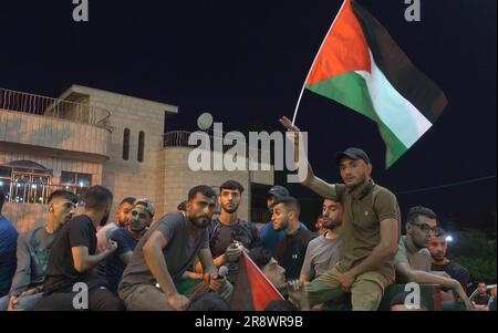 TURMUS AYYA, ISRAEL - JUNI 21: Palästinensische Männer halten palästinensische Flaggen während der Beerdigung eines 27-jährigen Mannes, der als Omar Qatin identifiziert wurde, der während eines Siedlerschlags durch die Stadt Turmus Ayya im Westjordanland, die sich am 21. Juni 2023 in der Nähe der israelischen Siedlung Shilo im Westjordanland, Israel, befindet, erschossen und getötet wurde. Hunderte israelischer Siedler starteten einen Angriff auf die palästinensische Stadt Turmus Ayya, warfen Steine auf Häuser und zündeten Dutzende Autos und Häuser an. Kredit: Eddie Gerald/Alamy Live News Stockfoto