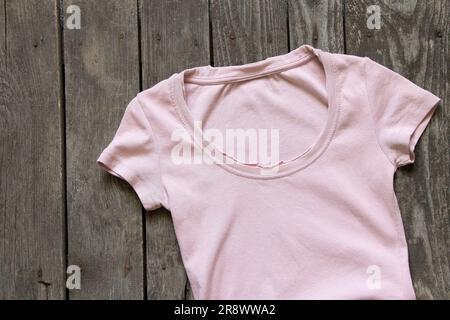 Pinkfarbenes Damen-T-Shirt flach liegend auf rustikalem braunem Hintergrund, Damenbekleidung, Mode Stockfoto