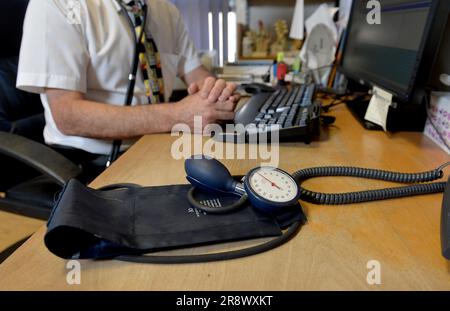 Legen Sie das Foto eines Allgemeinarztes vom 10.09/14 am Schreibtisch ab. Ärzte – und insbesondere GPS – haben mit ihrer Arbeitsbelastung zu kämpfen, können nicht immer eine sichere Patientenversorgung bieten und sind laut einer großen Umfrage dem Risiko eines Burn-out ausgesetzt. Die Umfrage von mehr als 4.000 Ärzten im Vereinigten Königreich, für die Aufsichtsbehörde der General Medical Council (GMC), ergab einen Rückgang der Arbeitszufriedenheit, Menschen, die länger arbeiten und Schwierigkeiten bei der Verwaltung der Patientenversorgung. Ausgabedatum: Freitag, 23. Juni 2023. Stockfoto