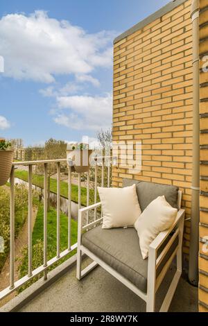 Ein Außenbereich mit einer Couch und einigen Pflanzen auf der anderen Seite des Gebäudes, vor einem blauen Himmel Stockfoto