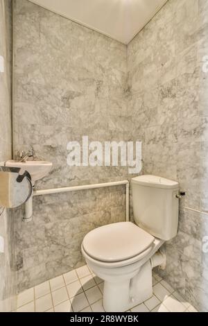 Ein Badezimmer mit Marmorwänden und weißen Fliesen auf dem Boden sowie eine Toilette in der Ecke des Zimmers Stockfoto
