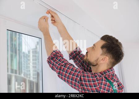 Arbeiter in einheitlich hängenden Fenstervorhängen in Innenräumen, niedrige Sicht Stockfoto