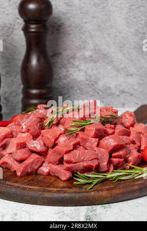 Rohes Rindfleisch in Würfel geschnitten. Gewürfeltes Rind oder Lamm auf einem Servierbrett aus Holz Stockfoto