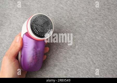 Frau, die den Rasierer in der Nähe eines hellgrauen Tuchs mit Fusseln hält, Nahaufnahme. Platz für Text Stockfoto