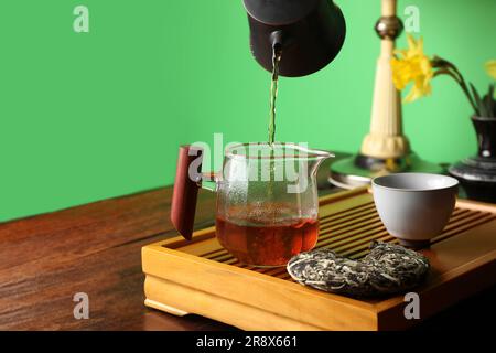 Frisch gebrühten pu-erh-Tee während der traditionellen Zeremonie am Holztisch in den Pitcher gießen. Platz für Text Stockfoto