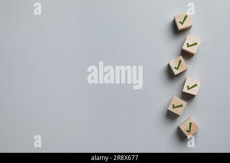 Holzwürfel mit Häkchen auf hellgrauem Hintergrund, flach verlegt. Platz für Text Stockfoto