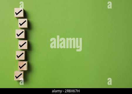 Holzwürfel mit Häkchen auf grünem Hintergrund, flach verlegt. Platz für Text Stockfoto